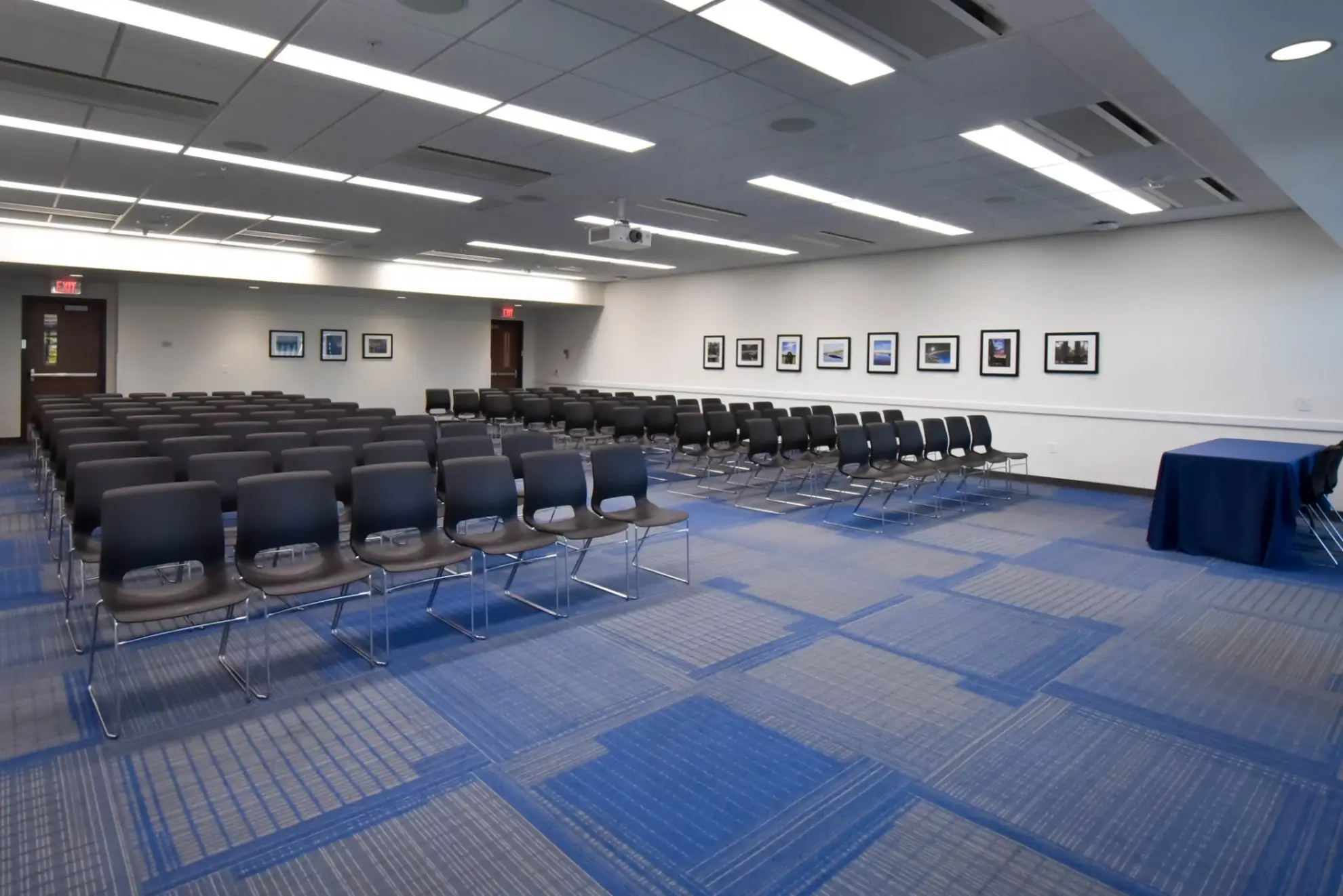 A large conference room with rows of chairs, a table, and framed pictures on the wall.